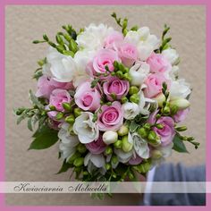 a bridal bouquet with pink and white flowers is held by someone's hand