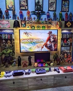 there are many action figures on the table in front of the television screen and shelves full of toys