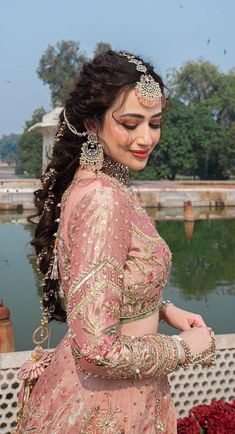 a woman in a pink lehenga standing by the water