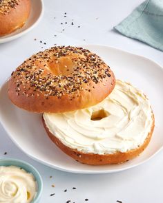 two bagels with cream cheese and sprinkles sit on a white plate