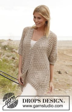 a woman is standing on the beach with her hand in her pocket and wearing a knitted cardigan