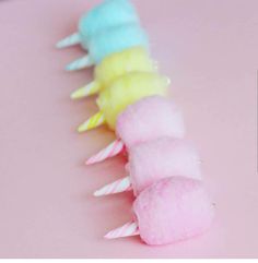 a row of colorful cotton candy sticks on a pink surface