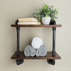 a shelf with towels and a potted plant on it next to a wall mounted towel rack