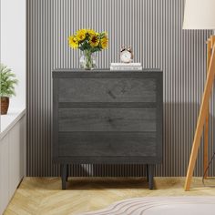 a nightstand with flowers and a clock on it next to a wallpapered room