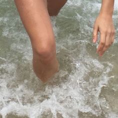 a woman standing in the ocean with her feet in the water