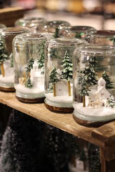 several glass jars with snow and trees in them