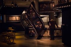 a woman standing in front of a movie projector with pictures on the wall behind her