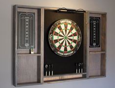 a dart board mounted to the side of a wall with darts and chalk boards on it