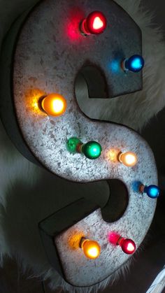 the letter s is lit up with colorful lights on it's sides and surrounded by fluffy white fur