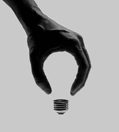 a person's hand holding an energy saving light bulb in black and white photo