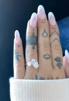 a woman's hand with tattoos and a diamond ring on it, holding onto her fingers