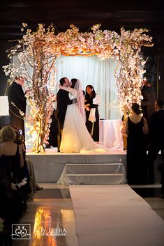 a bride and groom kissing in front of an altar