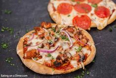 two pizzas sitting on top of a table covered in toppings