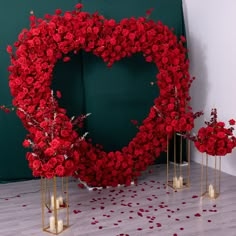 a heart - shaped wreath with candles and flowers on the floor in front of it