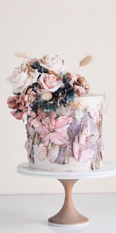 a white cake with pink flowers and feathers on top