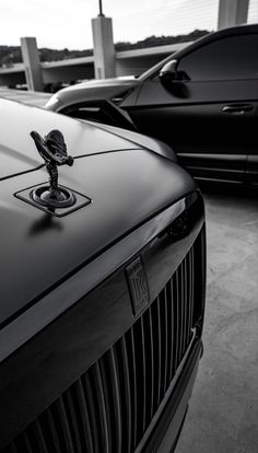 two cars parked next to each other in a parking lot, one is black and white