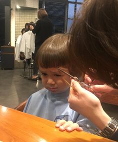 a little boy getting his hair cut by an adult