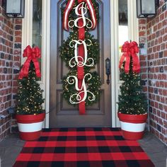 two christmas wreaths with monogrammed letters and red ribbon on the front door