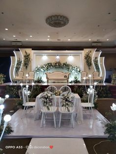 a wedding setup with white chairs and flowers