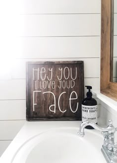 a bathroom sink with a wooden sign above it that says hey you love your face