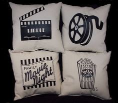 four pillows with movie themed designs are on a black surface and one has a popcorn bucket, the other is a film reel