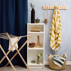 an ironing board and clothes rack in front of a blue wall with striped towels on it