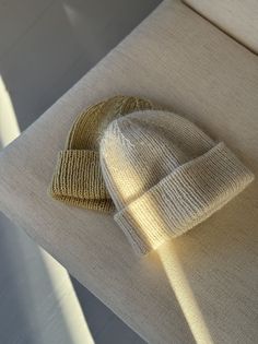 a knitted hat sitting on top of a white couch next to a window sill