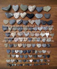 rocks arranged in the shape of hearts on a wooden surface with a quote written above them