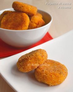 two pieces of fried food on a white plate next to a bowl of dipping sauce