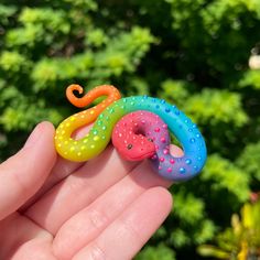 a hand is holding three small plastic toys in the palm, with trees in the background