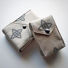 two small wallets with designs on them are sitting next to each other and one has a button in the middle