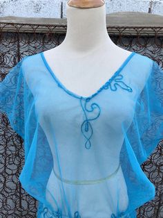 "Sheer nylon sky blue top simply slips on overhead. Trimmed with same sky blue color embroidery & sequins. Lovely blue beaded trim hemline. Three rows of elastic at waistline. Hemline has side slits on either side up to waist. No tags on this vintage garment. Very good vintage condition. Fits women size medium with further measurements of: Shoulder to hem = 32\" Pit to pit = 24\" Waist = Comfortably up to 30\" Hips = open" Embellished Blue V-neck Top, Blue Embellished V-neck Top, Fitted Blue Beaded Tops, Blue Beaded Tops For Spring, Beaded Blue Tops For Spring, Spring Blue Beaded Tops, Blue Bohemian Beaded Top, Bohemian Beaded Blue Top, Bohemian Blue Beaded Top