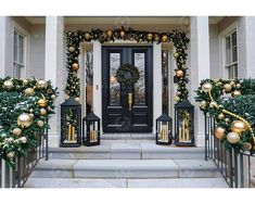 christmas decorations on the front steps of a house with lanterns and wreaths around it