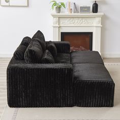 a black couch sitting on top of a white floor next to a fire place in a living room