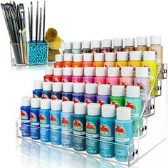 an assortment of pens and markers in a clear holder with acrylic paint on it