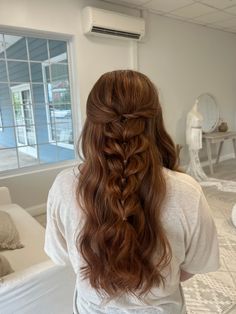 a woman with long red hair is standing in front of a bed and looking out the window