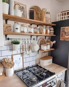 a stove top oven sitting inside of a kitchen next to wooden shelves filled with pots and pans