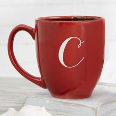 a red coffee mug with the letter c on it