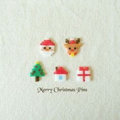 four christmas pins with santa claus, reindeer and tree on them sitting on a piece of white fabric