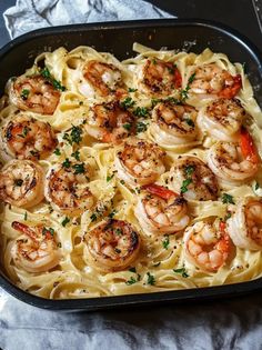 a pan filled with pasta and shrimp on top of a table