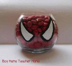 a glass bowl filled with red and black candies on top of a white table