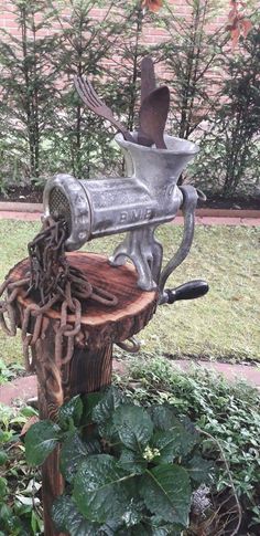 a metal object sitting on top of a tree stump in the middle of a garden