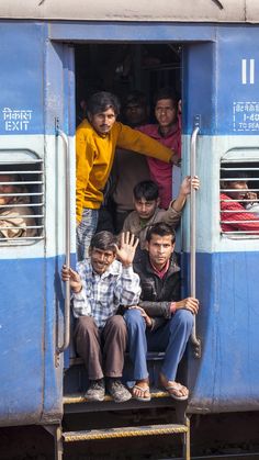 people are waving from the open door of a train