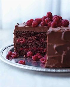 a piece of chocolate cake with raspberries on top and one slice missing from it