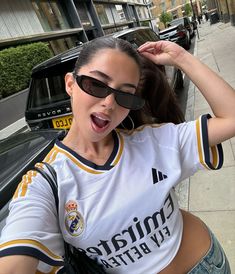 a woman with sunglasses on her head standing next to a car