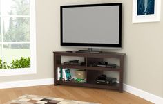 a flat screen tv sitting on top of a wooden entertainment center next to a window