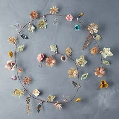 an arrangement of flowers arranged in the shape of a circle on a gray surface with leaves and acorns