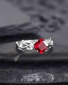 a red stone ring sitting on top of a rock