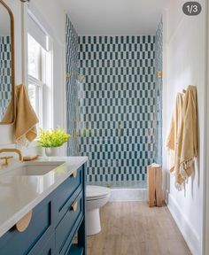 a bathroom with blue and white tiles on the walls, wood flooring and vanity