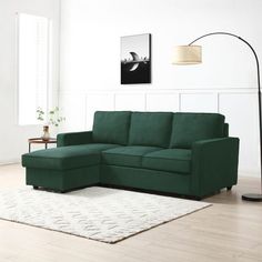 a green couch sitting on top of a white rug in a living room next to a lamp